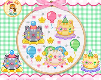 Op de afbeelding: Een ronde houten borduurring met een kruissteekpatroon van drie gestileerde katten met feesthoedjes en kragen, omringd door kleurrijke ballonnen, gele sterren en kleine roze hartjes, afgewerkt met een roze strik.