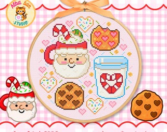 Op de afbeelding: Een kruissteekpatroon in een houten borduurring met een Kerstman-mok met zuurstok, een glas melk met een zuurstokhart, twee koekjes met hartjespatroon en diverse kleine hartjes- en spikkeltjesmotieven. Bovenaan zit een perzikkleurig lint.