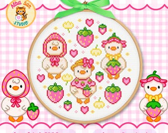 Op de afbeelding: Een kruissteekpatroon in een houten borduurring met drie witte eendjes in aardbei-thema hoedjes en outfits, omringd door kleine roze hartjes, gele bloemetjes en roze aardbeien, afgewerkt met een felgroene stoffen strik.