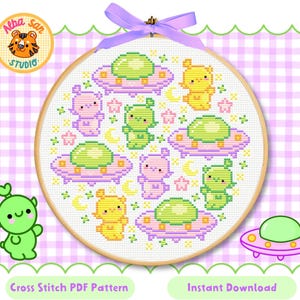 Puede incluir: Un patrón de punto de cruz en un aro de madera con un diseño repetido de lindos extraterrestres, ovnis, estrellas y lunas en colores pastel. El texto "Cross Stitch PDF Pattern" y "Instant Download" son visibles.
