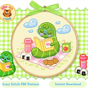May include: Cross-stitch pattern featuring a green worm wearing glasses and reading a book, surrounded by picnic items. The design is set in a wooden embroidery hoop with a green ribbon. The text "Cross Stitch PDF Pattern" and "Instant Download" are visible.