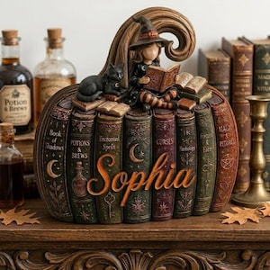 Peut inclure: Une sculpture décorative en forme de citrouille composée de livres anciens empilés avec des titres comme Book of Shadows, Potions & Brews, Enchanted Spells, Curses, Herbology et Magic & Rituals. Une figurine de sorcière et un chat noir sont posés dessus.