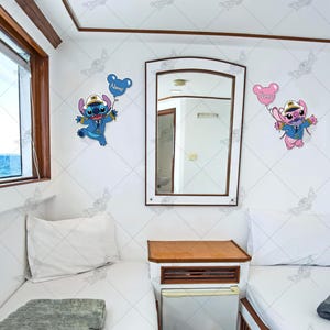 Puede incluir: Dos personajes de Stitch con globos azules y rosas, uno con un sombrero de capit&aacute;n, el otro con un lazo rosa. Los personajes est&aacute;n en una pared blanca con un espejo y dos camas blancas con mantas grises.