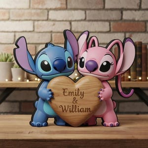 Può includere: Un set di statuine blu e rosa con personaggi dei cartoni animati che tengono un cuore di legno. Il cuore è inciso con i nomi "Emily & William". Lo sfondo comprende un muro di mattoni e una mensola di legno con libri e piante.