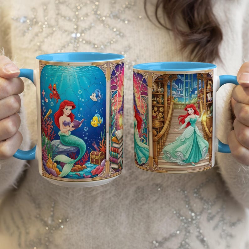 Pu&ograve; includere: Due tazze in ceramica con manici e bordi blu. Una tazza raffigura Ariel che legge sott'acqua, l'altra mostra Ariel su una scala. Entrambe le tazze hanno illustrazioni colorate e dettagliate.