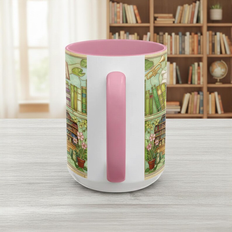 Pu&ograve; includere: Tazza in ceramica bianca con interno e manico rosa. La tazza presenta un'illustrazione dettagliata di una scena di biblioteca con libri, fiori e una tromba. Il design avvolge la tazza, creando un'immagine coerente.