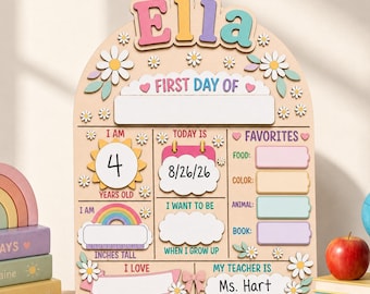 May include: A wooden arch-shaped sign with the name Ella at the top. It features sections for First Day Of, age 4, date 8/26/26, favourites, height, career goals, and teacher Ms. Hart. The board is decorated with pastel daisies and rainbow graphics.