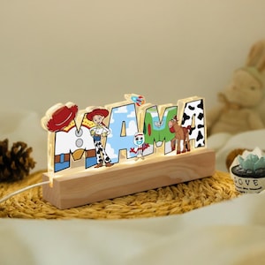 May include: A wooden night light with the word "MAMA" illuminated with warm white lights. Each letter features a different character from the Toy Story movie, including Woody, Jessie, and Bullseye. The light sits on a wooden base.