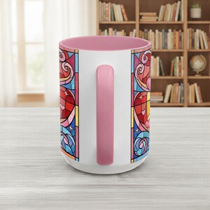 Puede incluir: Taza de cer&aacute;mica blanca con interior y asa rosa. La taza presenta un colorido dise&ntilde;o de vidriera con tonos rojos, azules, amarillos y rosas. El dise&ntilde;o incluye corazones y espirales.