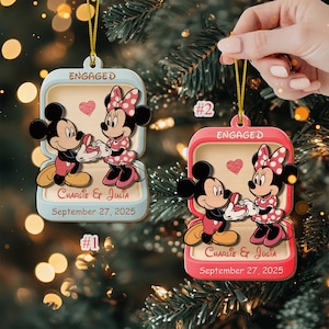May include: Two Mickey and Minnie Mouse engagement ornaments. Each ornament features the characters in a ring box, with the word "ENGAGED" at the top. The names "Charlie & Julia" and the date "September 27, 2025" are also displayed.