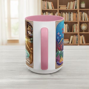 Pu&ograve; includere: Tazza in ceramica bianca con interno e manico rosa. La tazza presenta illustrazioni dettagliate di una scena di biblioteca e di una scena sottomarina con coralli, pesci e bolle. Il manico &egrave; di colore rosa pieno.