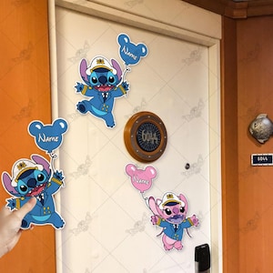 Puede incluir: Dos personajes Stitch azules y uno rosa sosteniendo globos con la palabra "Name" en ellos. Los personajes llevan gorras de capit&aacute;n y uniformes azules. Los personajes est&aacute;n en una puerta blanca con una placa redonda de metal marr&oacute;n con el n&uacute;mero "6044" en ella.