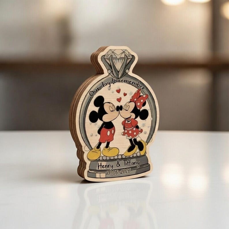 May include: Wooden wedding keepsake featuring Mickey and Minnie Mouse kissing inside a diamond ring design. The ring has the text "Our day to remember" and the names "Henry & Tiffany" with a date. The characters are in their classic outfits.