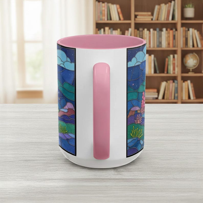 Puede incluir: Taza de cer&aacute;mica blanca con interior y asa rosa. La taza presenta un dise&ntilde;o de paisaje colorido con tonos azules, verdes y morados, que representa una escena nocturna con estrellas y nubes. El asa es de color rosa liso.