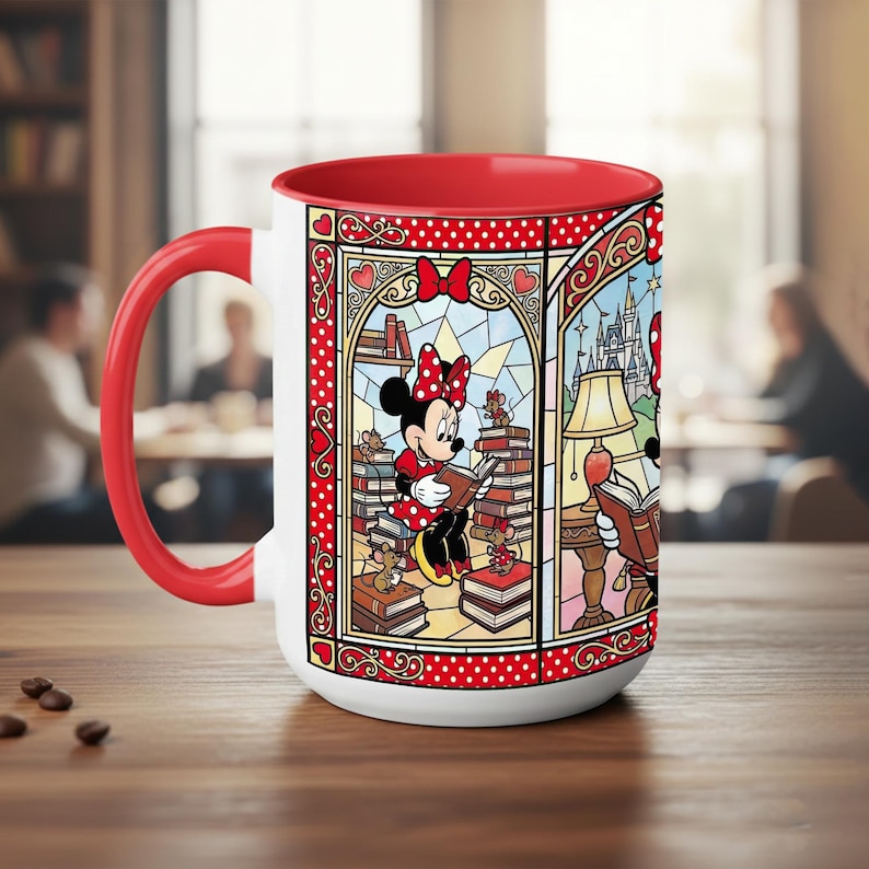Puede incluir: Una taza de cer&aacute;mica blanca con interior y asa rojos. La taza presenta un colorido dise&ntilde;o de vidriera de Minnie Mouse leyendo libros. El dise&ntilde;o incluye un lazo rojo, corazones y un castillo. La taza est&aacute; sobre una mesa de madera.
