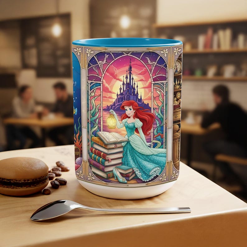 Pu&ograve; includere: Tazza in ceramica bianca con interno blu. Illustrazione in stile vetrata di una principessa dai capelli rossi che tiene una lanterna davanti a un castello. La principessa indossa un abito turchese. La tazza ha una base bianca.