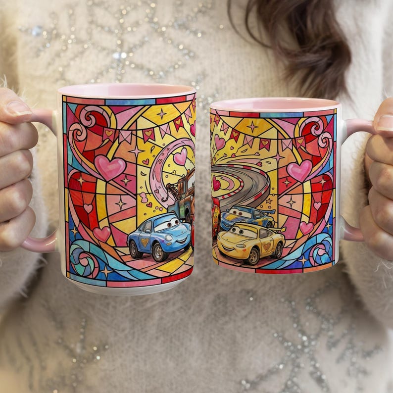 Puede incluir: Dos tazas de cer&aacute;mica con interiores y asas rosas. Cada taza presenta un colorido dise&ntilde;o de vidrieras con corazones, estrellas y coches de dibujos animados. Una taza tiene un coche azul y la otra tiene dos coches amarillos. Las tazas son sostenidas por una persona.