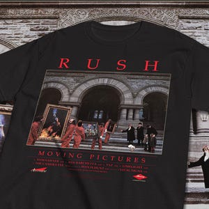 May include: Black t-shirt with the red band name "RUSH" above the "Moving Pictures" album art. The image depicts people carrying framed pictures. The album's song titles are listed below the image, along with the Anthem and Mercury logos.