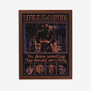 May include: A framed poster with a dark background featuring a figure in a dark robe holding a cube. The text "HELLRAISER" is at the top of the poster. The text "You desire something. They demand everything." is below the figure. There are four smaller images of cubes below the text.