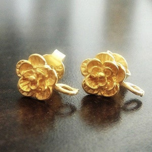 May include: A pair of gold-tone flower-shaped earring findings with a loop on the side.