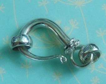 May include: Silver-toned metal clasp with a twisted rope design and a rounded ball. The clasp is designed to be used for jewelry or other crafts.