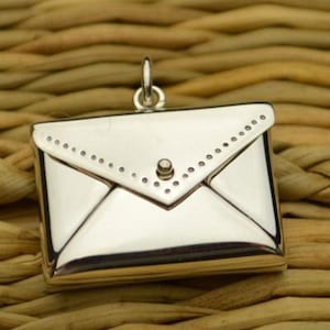 May include: A silver envelope charm with a small, round, silver button closure. The envelope has a dotted border around the edges.