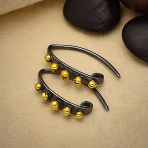 May include: A pair of silver hoop earrings with a row of gold beads along the bottom edge.