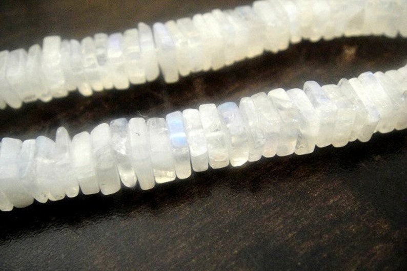 May include: A strand of white moonstone beads, each bead is rectangular and has a slightly iridescent shimmer.