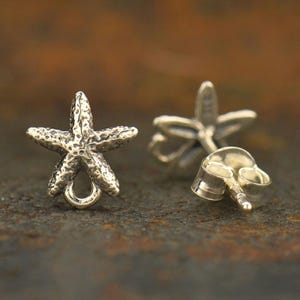 May include: A pair of silver starfish stud earrings. The earrings are made of sterling silver and feature a detailed starfish design.