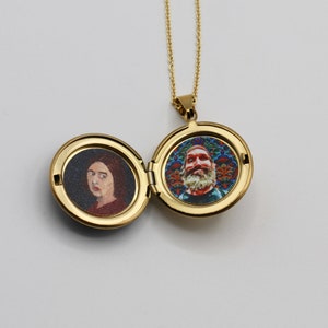 Puede incluir: Un collar con un medall&oacute;n de oro que contiene dos retratos. En un lado, una mujer con el pelo corto y casta&ntilde;o, en el otro, un hombre con barba sobre un fondo colorido.
