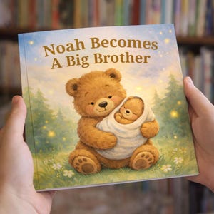 May include: A children's book titled "Noah Becomes A Big Brother" held by hands. The cover shows a brown teddy bear cradling a baby bear wrapped in a white blanket. The background depicts a forest scene with a blue sky and stars.