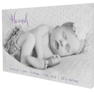 May include: Black and white photo of a newborn baby girl sleeping. The baby is wearing a white headband with a flower and a white onesie. The text "Hannah" is written in purple script above the baby. The text "February 11, 2015, 5:37am, 7 lbs. 13 oz., 20 1/2 inches" is written below the baby.