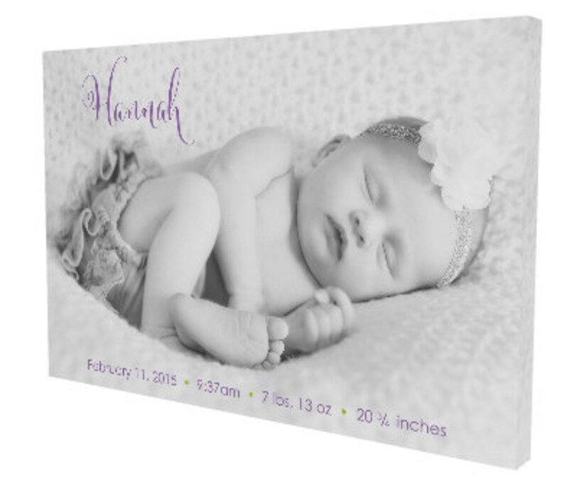 May include: Black and white photo of a newborn baby girl sleeping. The baby is wearing a white headband with a flower and a white onesie. The text "Hannah" is written in purple script above the baby. The text "February 11, 2015, 5:37am, 7 lbs. 13 oz., 20 1/2 inches" is written below the baby.