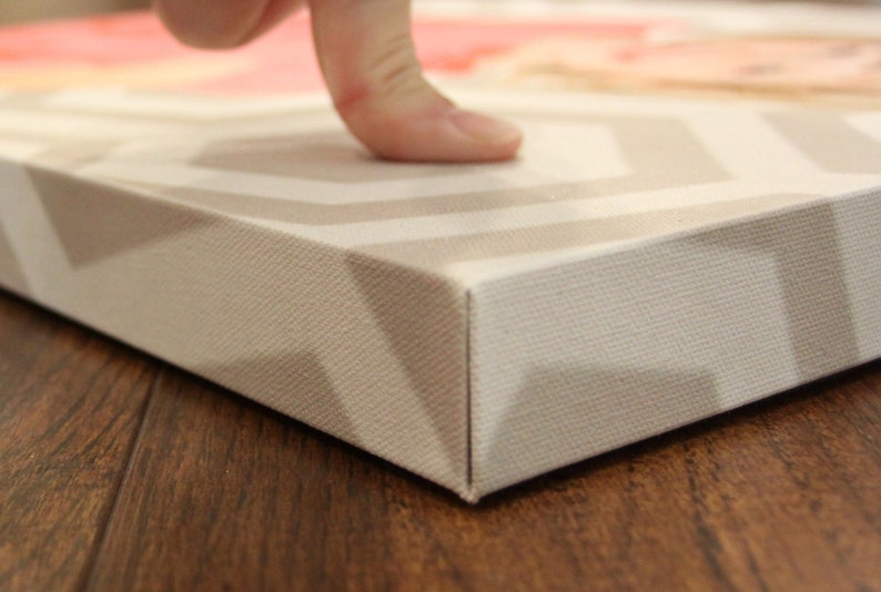May include: Close-up of the edge of a canvas print with a white and gray chevron pattern. The canvas is wrapped around the edges and the print is on a wooden surface.