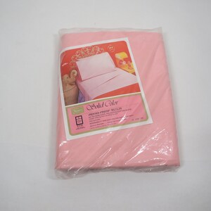 May include: A package of pink solid color Sears Perma-Prest muslin bed sheets. The packaging includes a label with an image of a bed with pink sheets and a pillow. The label also includes the words "Solid Color" and "Perma-Prest Muslin".