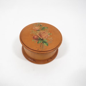 May include: A round wooden box with a hinged lid. The lid is painted with a floral design featuring pink and white roses.