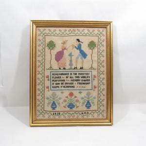 May include: A framed cross-stitch sampler with a couple in a garden setting. The sampler includes the text "Remembrance is the sweetest flower of all this world's perfuming memory guards it sun or shower friendship keeps it blooming." The sampler is dated 1930 and signed A.M.G.