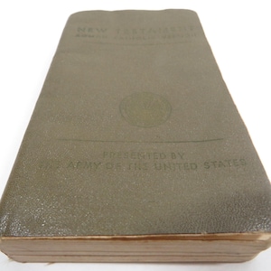 May include: A vintage olive green New Testament book. The cover features embossed text that reads "NEW TESTAMENT" and "ARMED FORCES EDITION". The book is presented by the "ARMY OF THE UNITED STATES".