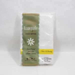 May include: A package of white Dan-Press percale pillowcases. The packaging features the text "tranquale by DAN RIVER" with a daisy graphic. The package also states "Needs No Ironing" and the pillowcase dimensions are 42 x 36 inches.
