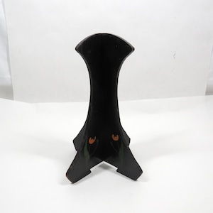 May include: A black wooden display stand with a curved, vertical silhouette and a tripod base. The front panels feature small, hand-painted orange tulip motifs with green stems, providing a subtle decorative detail on the dark, smooth surface.