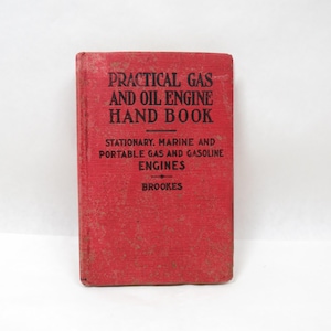 May include: A vintage red book titled "Practical Gas and Oil Engine Hand Book." The cover features black text with the subtitle "Stationary, Marine and Portable Gas and Gasoline Engines" and the author's name, Brookes.
