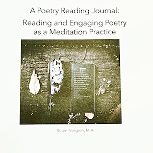 May include: A black journal with a white bookmark and a poem printed on a piece of paper. The journal is on a wooden surface with dried leaves scattered around it. The text on the page reads "A Poetry Reading Journal: Reading and Engaging Poetry as a Meditation Practice. Robin Norgren, M.A."