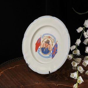 K&ouml;nnte beinhalten: Ein wei&szlig;er Keramikteller mit einem zentralen Portr&auml;t von K&ouml;nig Edward VIII. in Milit&auml;runiform, flankiert von einer roten Flagge und dem Union Jack, mit dem aufgedruckten Text H.M. KING EDWARD VIII und ACCESSION 21.I.1936 auf der Oberfl&auml;che.