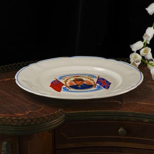 K&ouml;nnte beinhalten: Ein wei&szlig;er Keramik-Gedenkteller mit einem zentralen Portr&auml;t von K&ouml;nig Edward VIII. in Milit&auml;runiform, flankiert von zwei britischen Flaggen. Der Text lautet King Edward VIII und Accession 20.1.1936. Der Teller hat einen d&uuml;nnen blauen Rand.