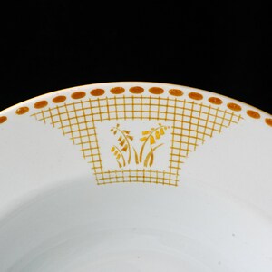 May include: White ceramic plate with a gold floral design and a gold grid pattern. The plate has a gold dotted border. The floral design is in the center of the plate.