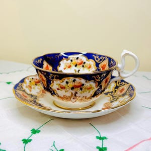 Taza y platillo antiguos Royal Albert “Heirloom” de color azul cobalto con base, diseño floral y dorado pintado a mano, 1925-1927, Inglaterra. Pieza de colección.