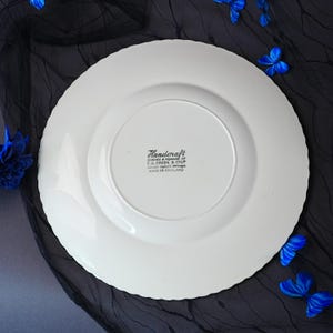 May include: A white ceramic plate with a scalloped edge, viewed from the underside. The center features black printed text reading Handcraft, Designed & Produced by T.G. Green & Co Ltd, Church Gresley Potteries, Made in England.