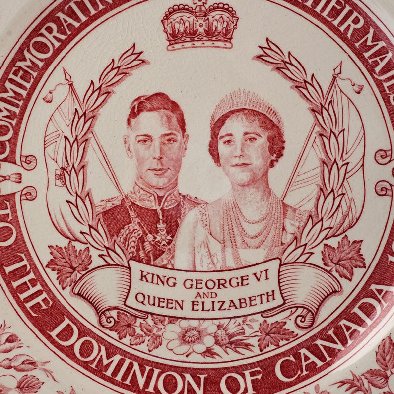 May include: A commemorative ceramic plate featuring a red and white transfer print of King George VI and Queen Elizabeth. The design includes a crown, flags, maple leaves, and the text: COMMEMORATION TO THE DOMINION OF CANADA, KING GEORGE VI AND QUEEN ELIZABETH.