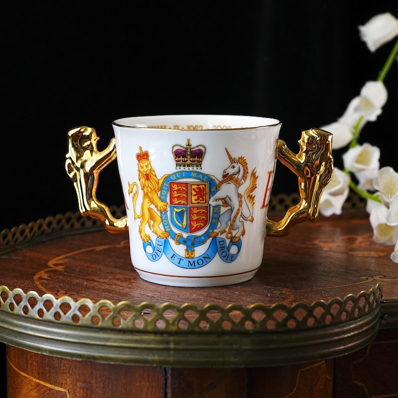 Copa de porcelana fina vintage Paragon del Jubileo Dorado de la Reina Isabel II: dos asas doradas con forma de león, escudo real, letras doradas en el borde, 2002. imagen 1