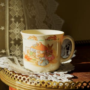 Tazza per bambini vintage Royal Doulton Bunnykins – Scena di asilo nido “Casa delle bambole” con bordo di coniglietti che corrono – Fine Bone China inglese (anni &#39;80)